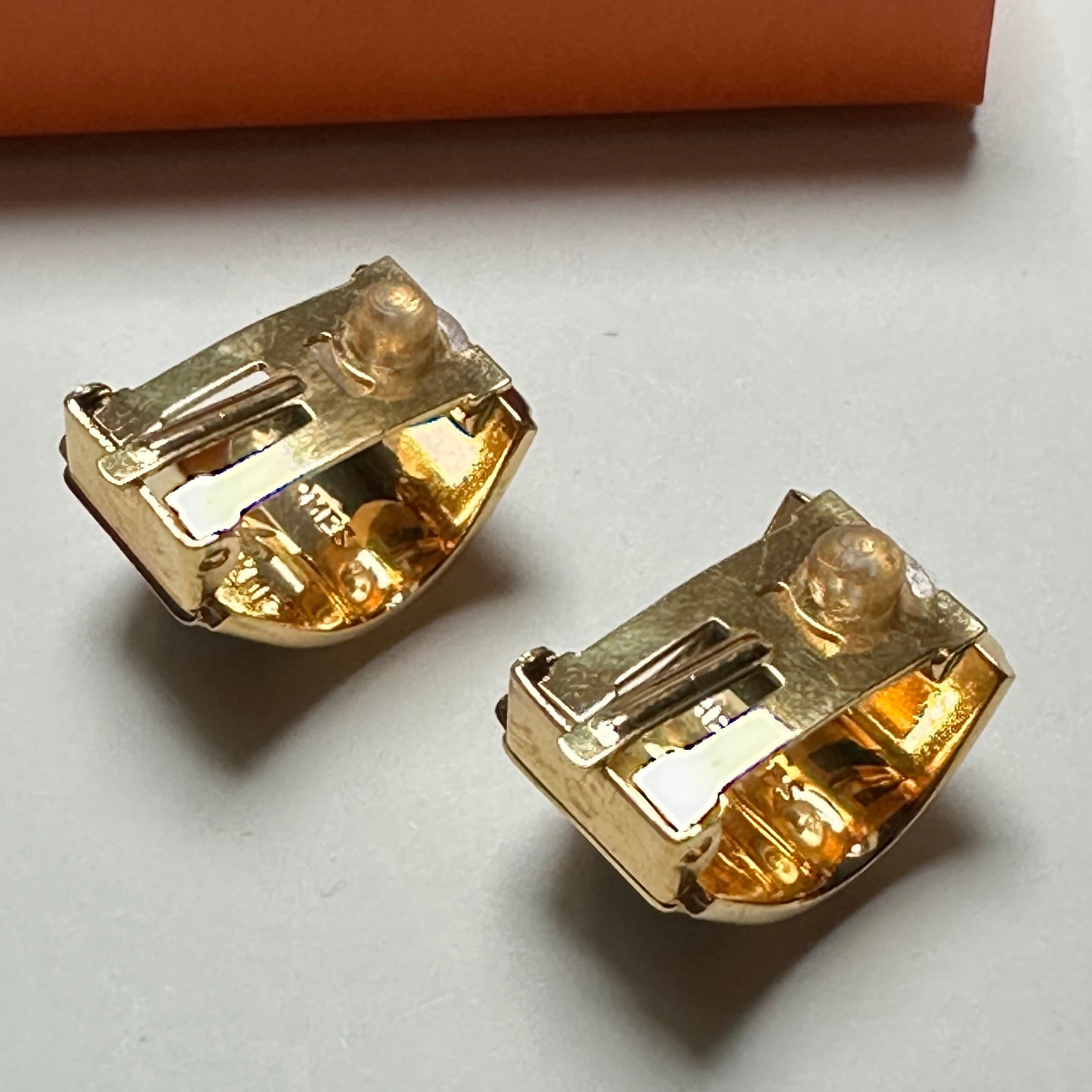 État de la dorure au dos des clips Hermès vintage, montrant un plaquage or brillant et soigné.