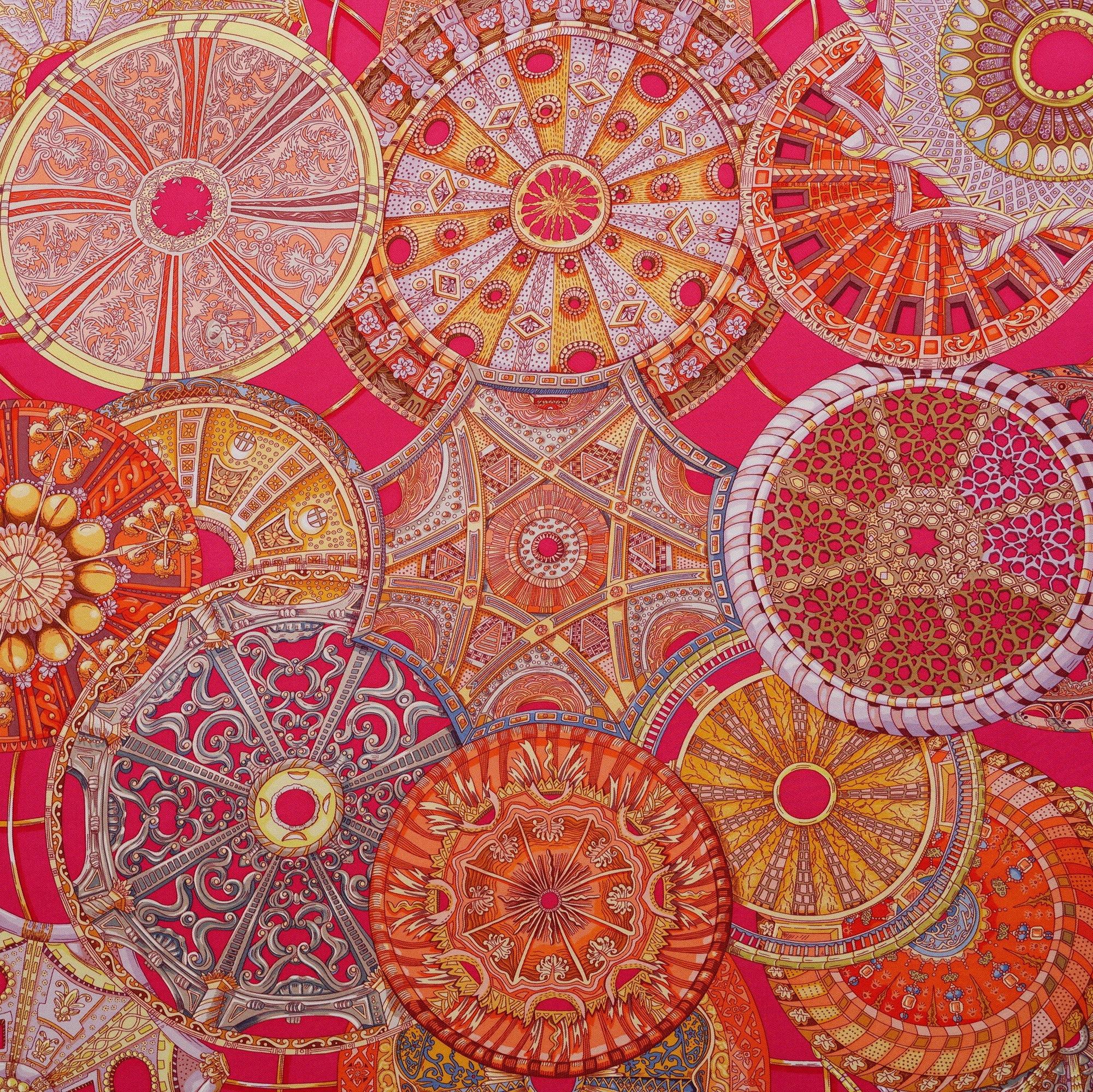Détail macro du cœur du foulard Hermès Les Dômes Célestes, mettant en valeur la précision des rosaces architecturales or et blanches sur le fuchsia.