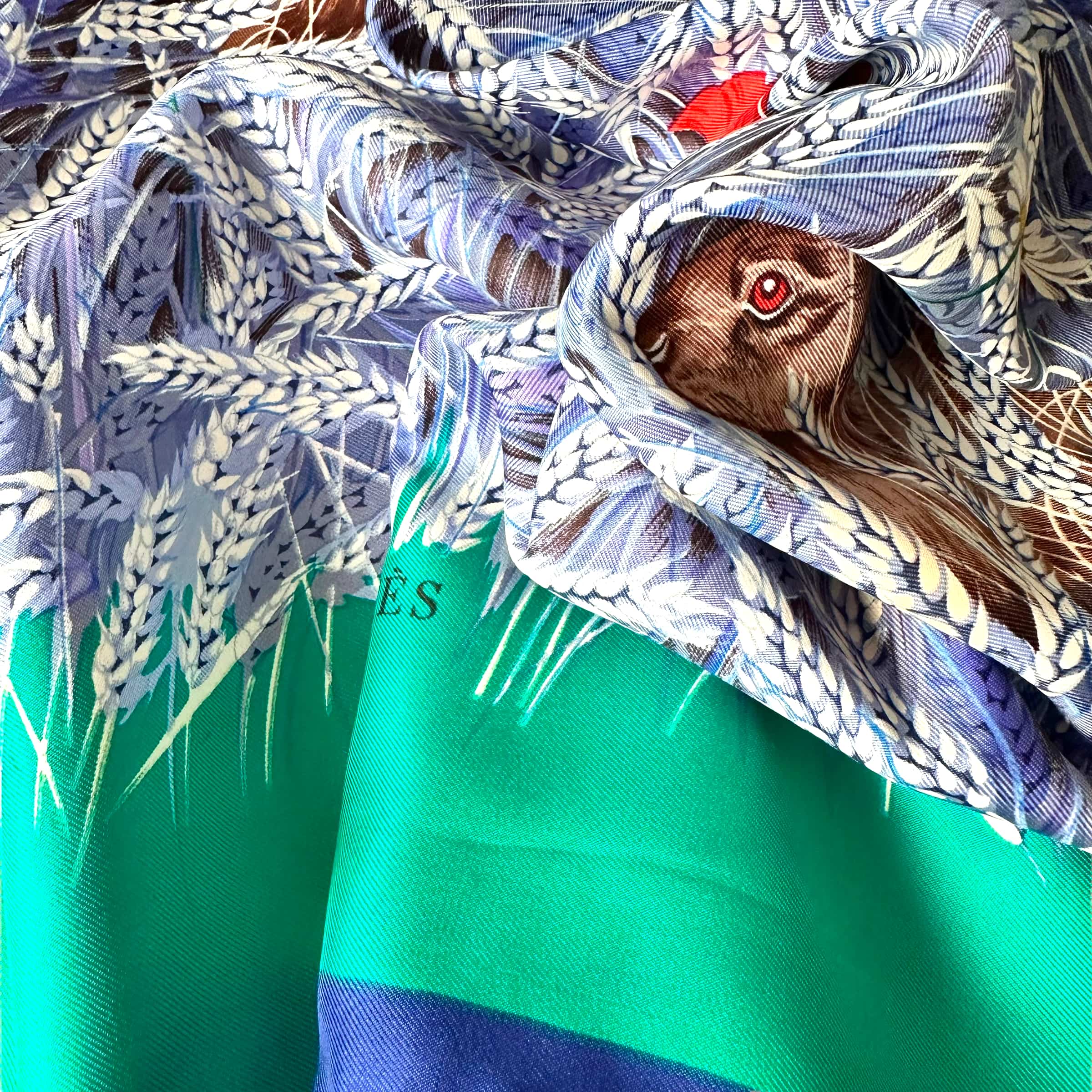 le foulard porté palette de vert et bleu on apperçoit un lapin cahe dans un plis du foulard