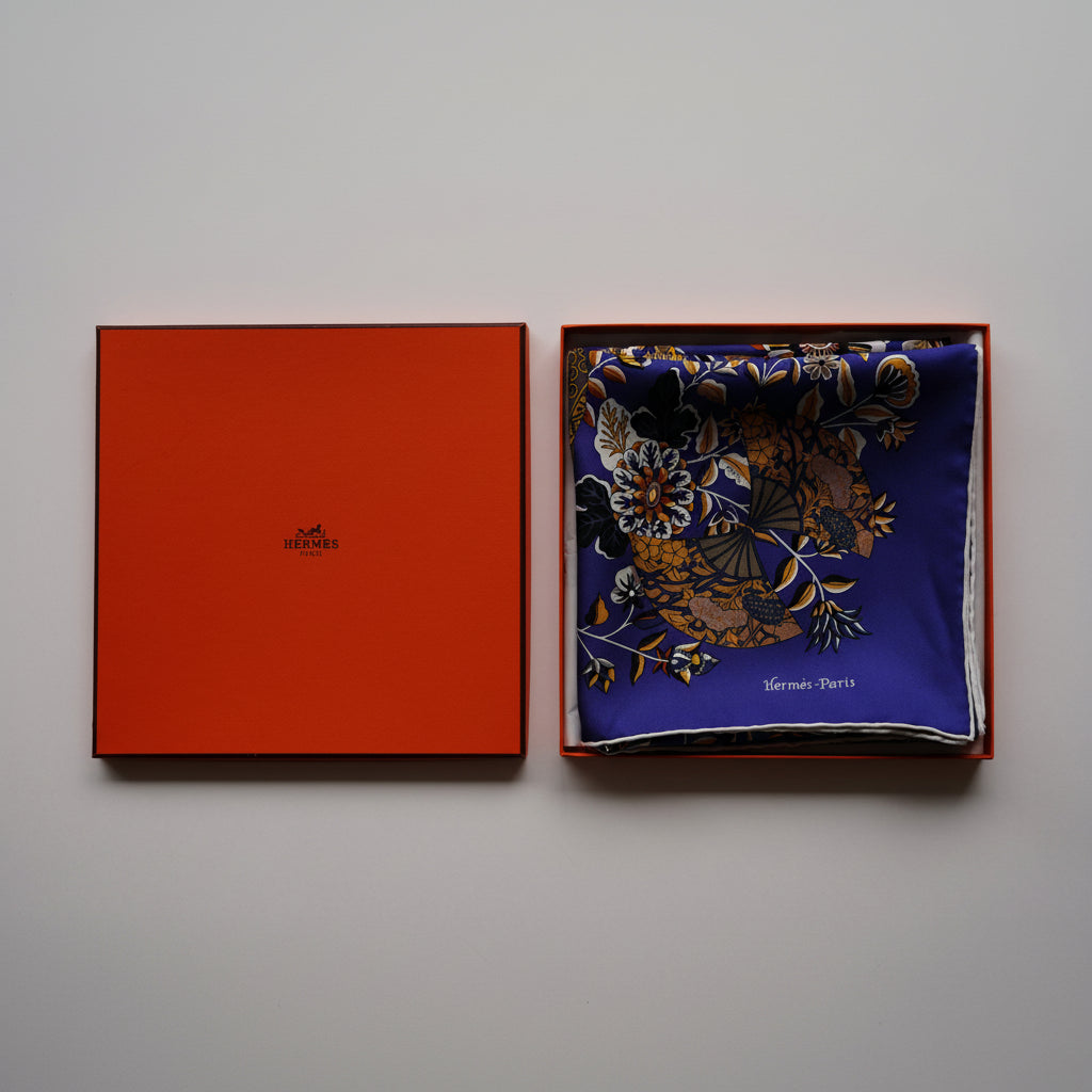 Présentation du foulard Hermès Fleurs et papillons de tissus bleu dans sa boîte orange d'origine ouverte, état neuf.
