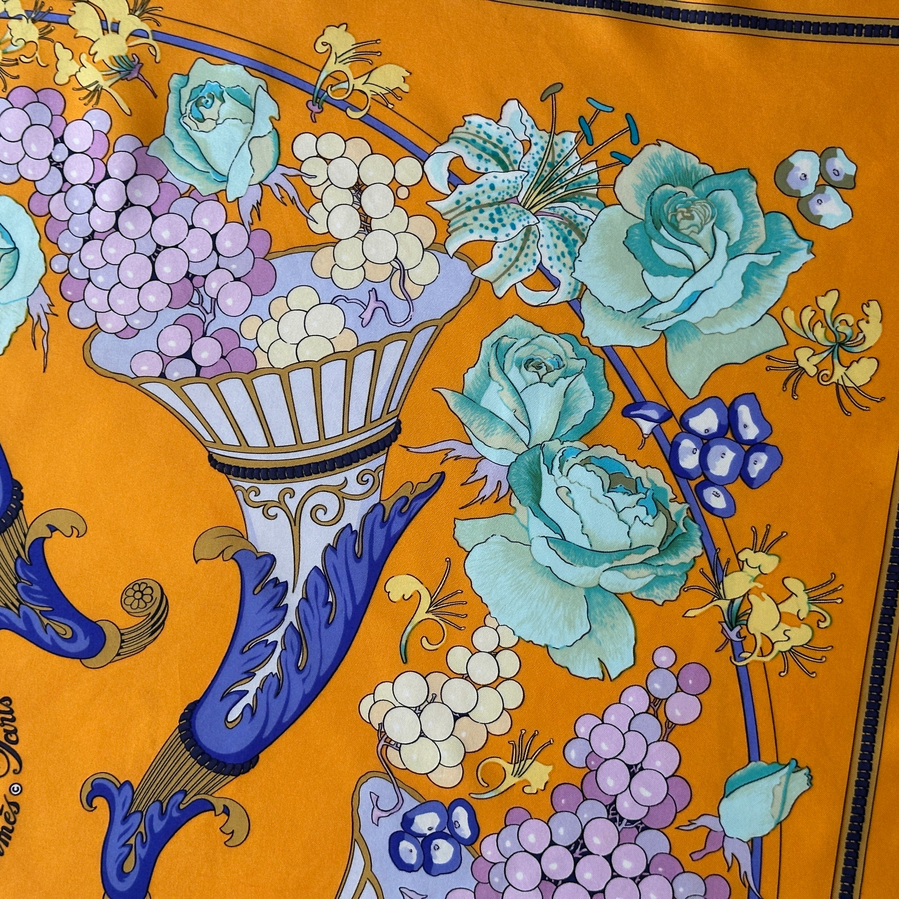 Détail richement coloré : grappes de raisins mauves et roses bleu pâle jaillissant d'une corne d'abondance sur soie jaune safran.