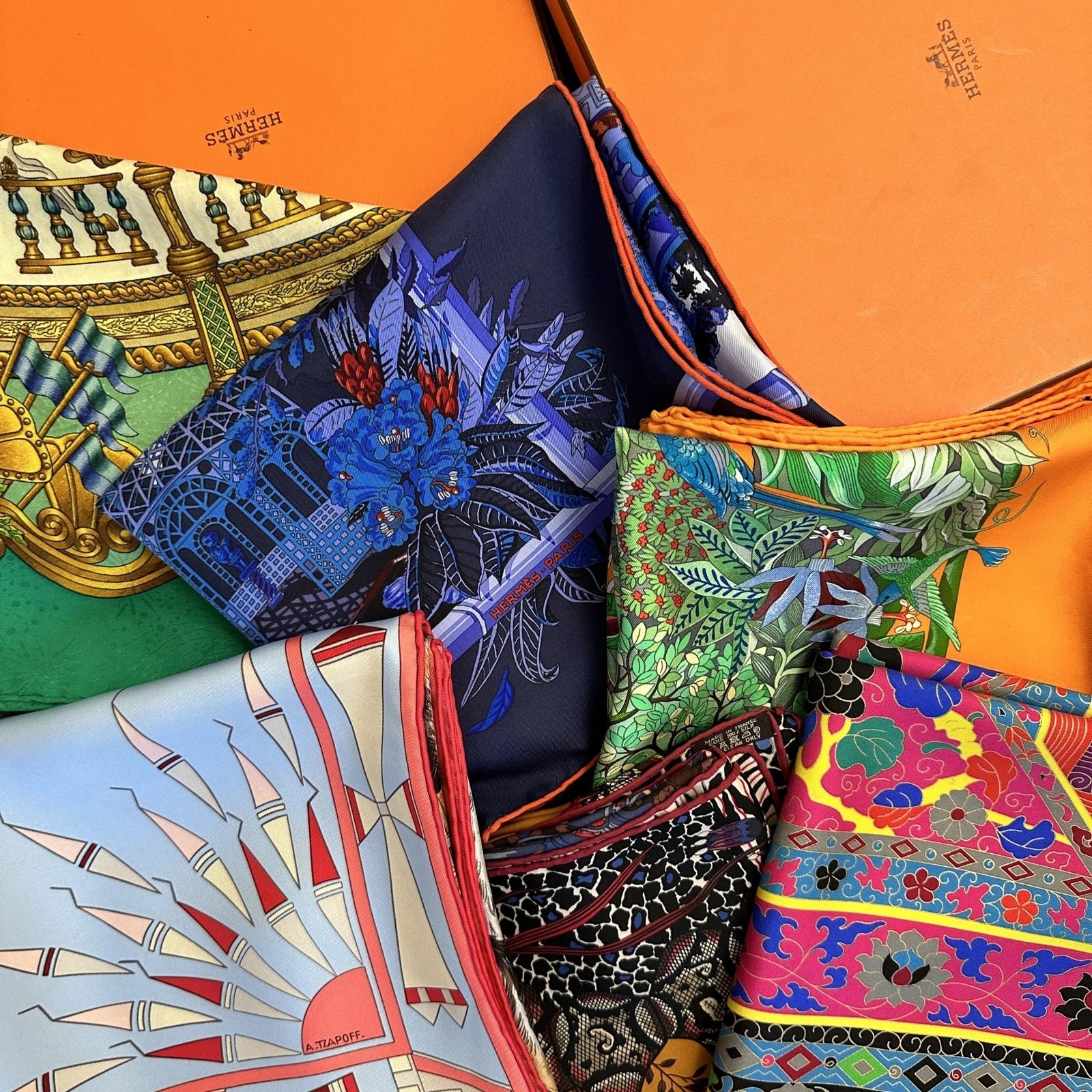 collection de carrés Hermès de différentes couleurs avec leur boîte